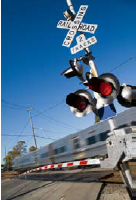 An at-grade rail crossing with a train traveling through.