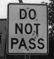 Photo of a 'DO NOT PASS' sign hit by several gunshots