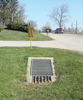 Photo. This image shows a grated inlet that is flush with the ground.
